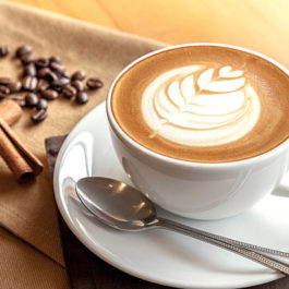 Cup of cafe' latte with coffee beans and cinnamon sticks